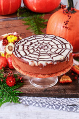 Halloween chocolate spider web cake and pumpkins around.
