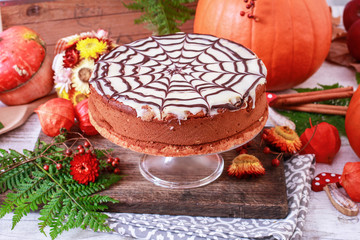 Halloween chocolate spider web cake and pumpkins around.