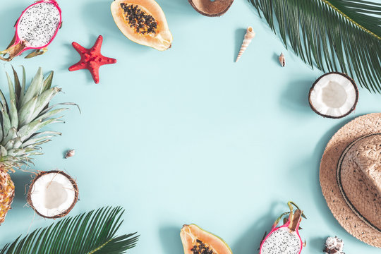 Summer composition. Tropical palm leaves, hat, fruits on blue background. Summer concept. Flat lay, top view, copy space