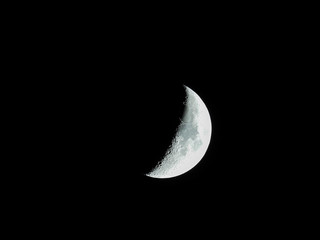 a very sharp close-up of the rising crescent moon in the night sky