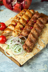 Plates of meat with barbecue and kebab, on gray background