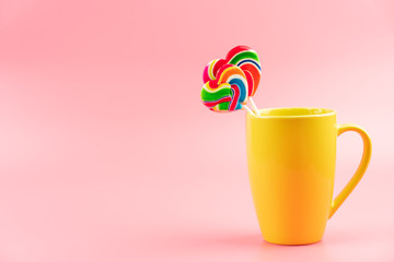 Multicolored lollipops in a container on a pink background
