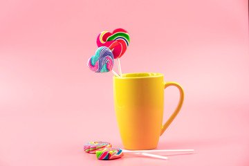 Multicolored lollipops in a container on a pink background