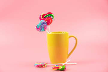 Multicolored lollipops in a container on a pink background