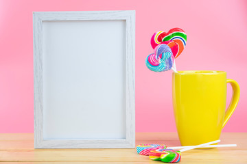 Multicolored lollipops in a container on a pink background with copy space