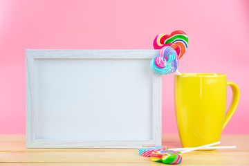 Multicolored lollipops in a container on a pink background with copy space