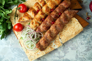 Plates of meat with barbecue and kebab, on gray background