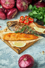 Grilled dorado fish and salmon steak on a wooden board 