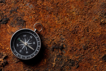 Fototapeta na wymiar Magnetic compass on rough rusty background
