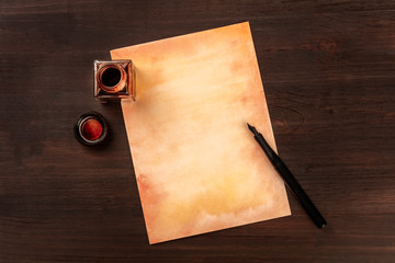 A vintage background with a nib pen on a piece of old paper, with an ink well, shot from above on a...