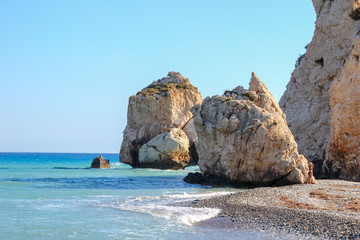 Structure of rocks on the bank of the Mediterranean Sea in beams of the sunset sun against the background of blue water