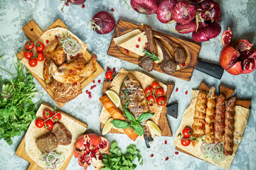 Plates of meat with barbecue and kebab, top view on gray background
