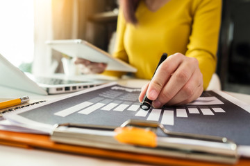 Fototapeta premium business documents on office desk with laptop and graph business diagram and Woman working at office.