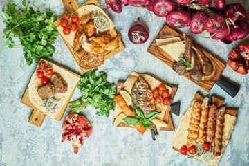 Plates of meat with barbecue and kebab, top view on gray background
