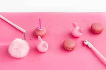 School stationery with unicorn pen,fur, macaroons on a pink background. Back to school creative table desk. Minimal food bakery concept. Flat lay top view with copy space -