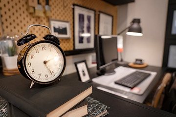 Retro alarm clock. Twenty minutes past Two o'clock in the morning Lamp light on overtime working in office. Vintage clockwise at office desk with computer. Deprivation and overtime working concept