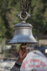 A Man's hand rings a temple bell at Gangotri in India.