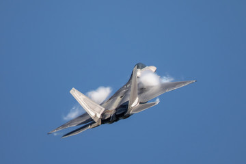 Fototapeta na wymiar Very close tail view of a F-22 Raptor, with afterburners on and condensation trails around the wings