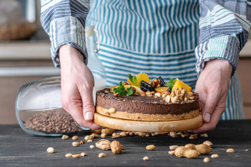 Hands decorated with chocolate cake orange and mint leaves with peanuts and nuts. Healthy raw desserts for vegan food