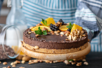Hands decorated with chocolate cake orange and mint leaves with peanuts and nuts. Healthy raw desserts for vegan food