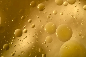 Oil drops in water on a colored background. Bright background with mustard color circles of different sizes. Blur, horizontal, place for text, plain color, toning. Concept of design.