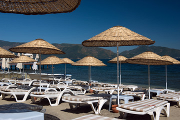 Beach. Umbrellas and chaise lounges, bright blue sky and sea. Travel and vacation concept