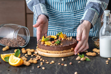 Hands decorated with chocolate cake orange and mint leaves with peanuts and nuts. Healthy raw desserts for vegan food