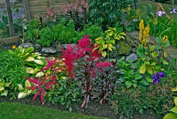 A small water feature in a decorative flower border with hostas and astilbes