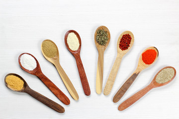 Assortment of spices in wooden spoons, white background
