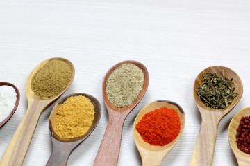 selective focus on Assortment of spices in wooden spoons, white background