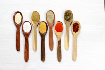 Assortment of spices in wooden spoons, white background