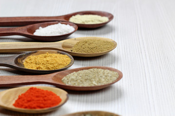 selective focus on Assortment of spices in wooden spoons, white background