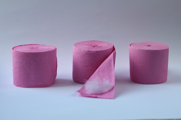 three pink rolls of toilet paper on a white background