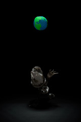 Plasticine Earth planet handmade above fantasy creature sculpture from plastic cups, forks and spoons, in selective light. Ecology Concept for Earth Hour, Earth Day, Ocean Day and other ECO dates.