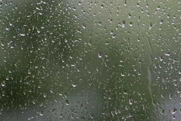 Raindrops on window glass during the rain close up. Natural background