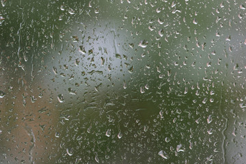 Raindrops on window glass during the rain close up. Natural background