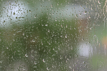 Raindrops on window glass during the rain close up. Natural background