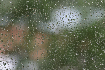Raindrops on window glass during the rain close up. Natural background