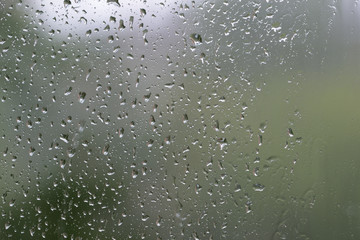 Raindrops on window glass during the rain close up. Natural background