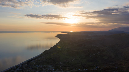 Aerial photography. Evening view of the sea and shore. Sunset over the water. Clouds in the sky.