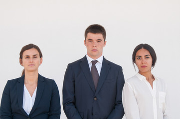 Fototapeta na wymiar Corporate portrait of serious successful business team. Three young business people standing for camera against white background. Business team concept