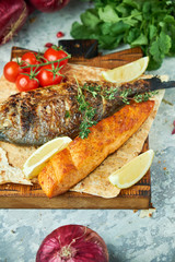 Grilled dorado fish and salmon steak on a wooden board 