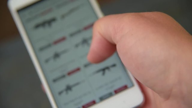 A man looking and chooses a weapons to buy on the site.