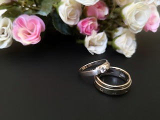 Closeup with wedding rings with beautiful roses flower background.