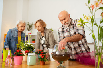 Pleasant nice man putting his hand in the vase