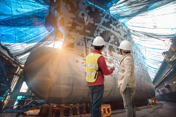 Stevedore, controller, Port Master, surveyor inspect the bulk head of commercial cargo ship in...