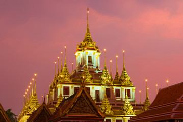 Obraz premium Top of the old chedi Loha Prasat of the Buddhist temple Wat Ratchanatdaram Varavihara close-up against the background of the sunset. Bangkok, Thailand