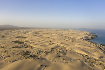 Fototapeta na wymiar Desert coastal aerial with golden yellow sand and blue sea background