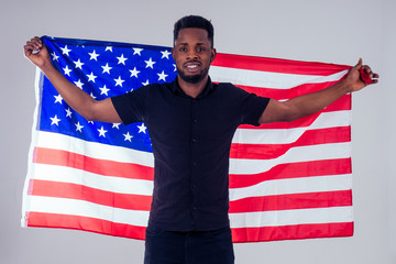 african american man looking at camera and proudly holding american flag at studio