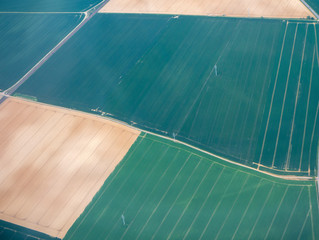 Earth's line. A vertical perspective of the ground's colors and shapes. Agricultural fields with green and brown colors. View from the airplane window